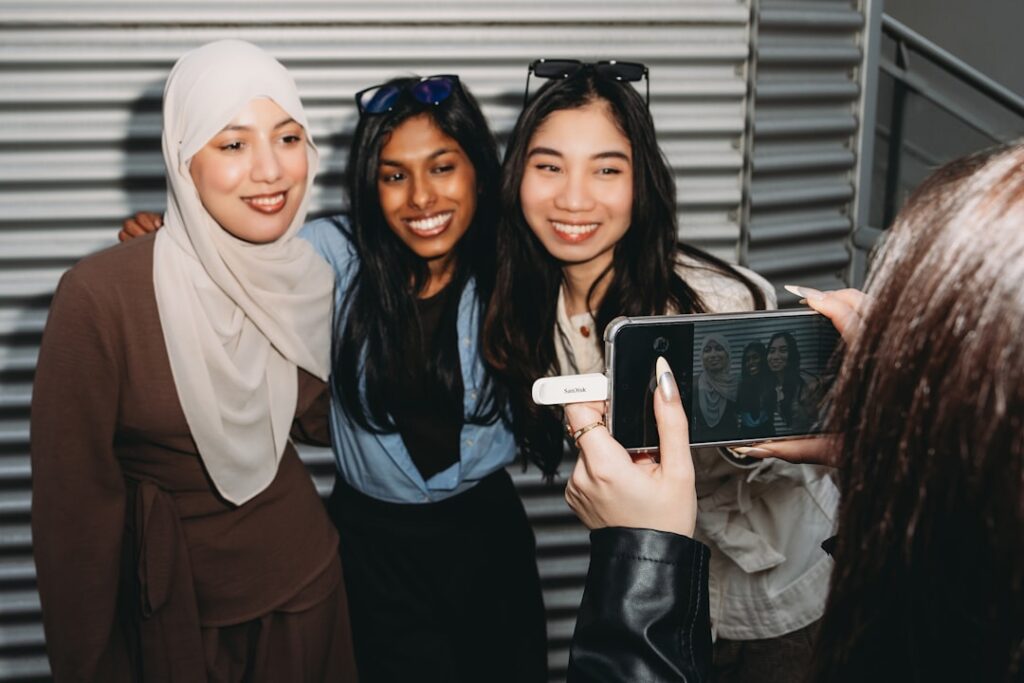 A person photographs three smiling women with a smartphone