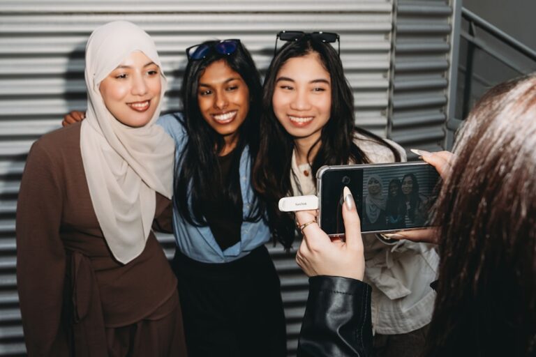 A person photographs three smiling women with a smartphone