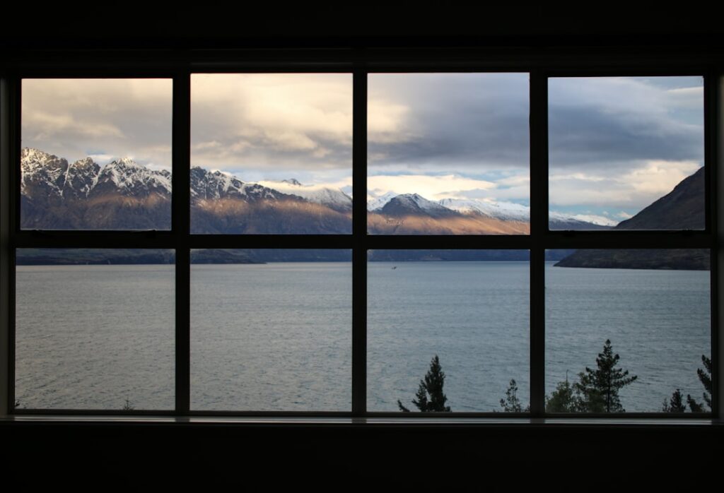 A view of a lake and snow-capped mountains through a large window