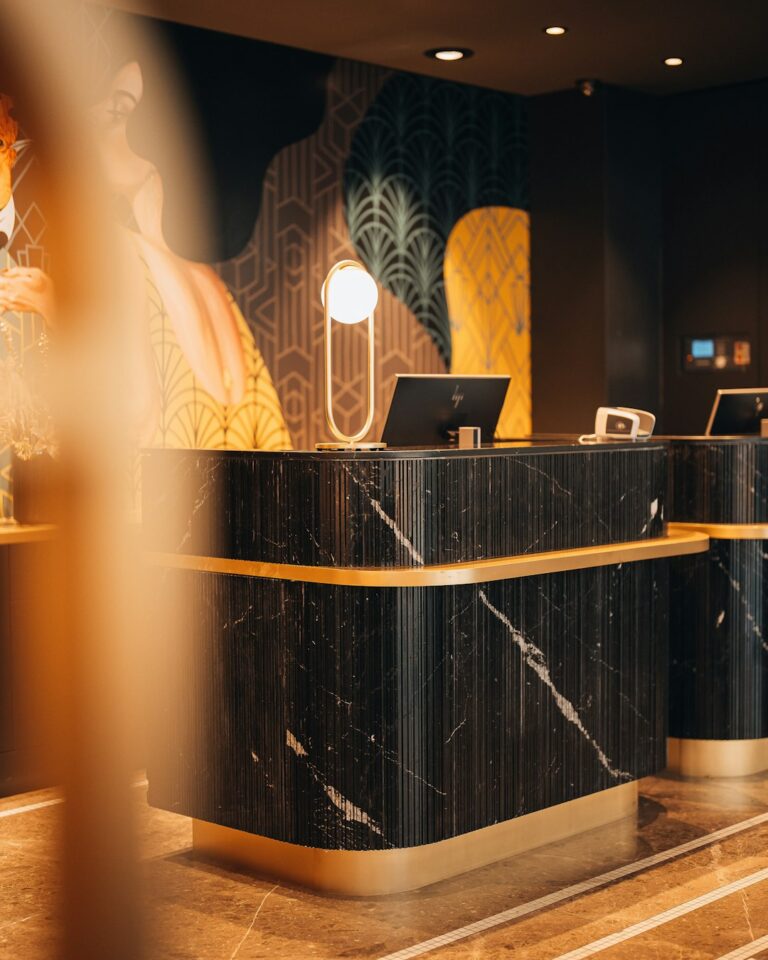 A black marble reception desk with gold trim in a hotel lobby